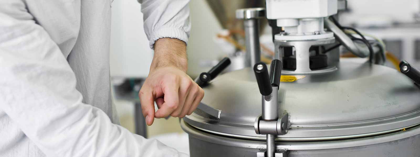 Photograph showing hands tightening down the lid to an industrial food mixer.